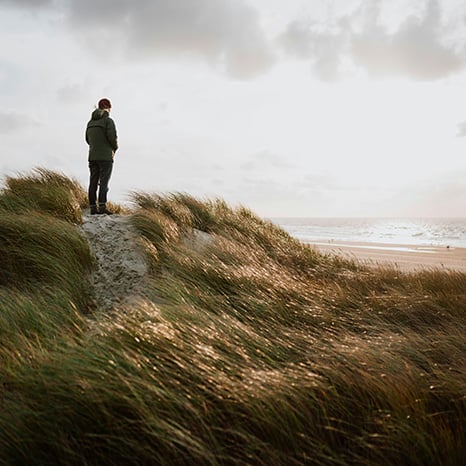 kvinna-står-på-gräskulle-vid-havet